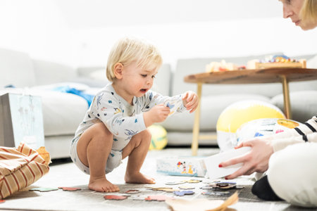 Parents playing games with child. Little toddler doing puzzle. Infant baby boy learns to solve problems and develops cognitive skills. Child development concept.の写真素材