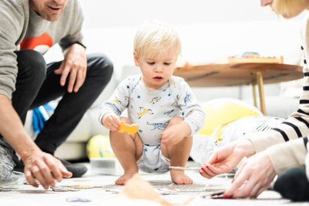 Parents playing games with child. Little toddler doing puzzle. Infant baby boy learns to solve problems and develops cognitive skills. Child development concept.の写真素材