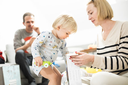 Cute little blond Caucasian toddler unpacking Christmas or Birthday present. Adorable small infant baby boy opening gift.の写真素材