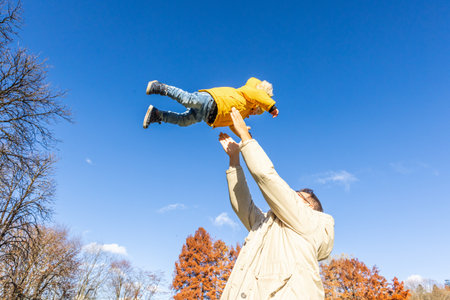 More, more,... dad, thats fun. Happy young father throws his cute little baby boy up in the air. Fathers Day, Father and his son baby boy playing and hugging outdoors in nature in fallの写真素材