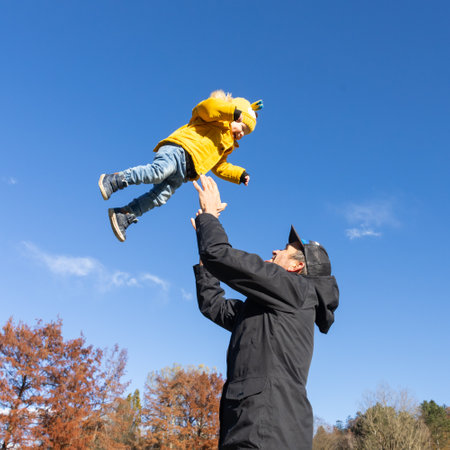 More, more,... dad, thats fun. Happy young father throws his cute little baby boy up in the air. Fathers Day, Father and his son baby boy playing and hugging outdoors in nature in fallの写真素材