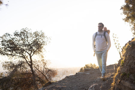 Young father carrying his infant baby boy son in backpack while tracking around Malaga, Spain in sunset. Family travel and vacation concept.の写真素材