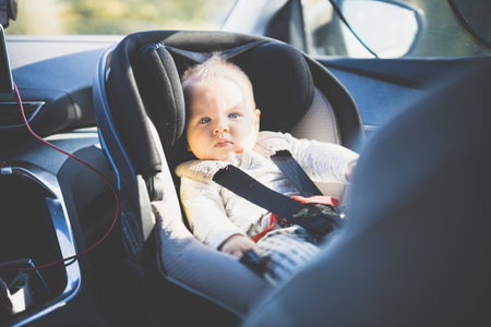 Cute little baby boy strapped into infant car seat in passenger compartment during car driveの写真素材
