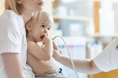 Small child being checked for heart murmur by heart ultrasound exam by cardiologist as part of regular medical checkout at pediatricianの写真素材