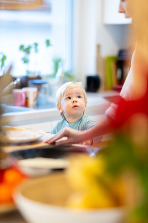 Mother and little toddler baby boy making pancakes for breakfast together in domestic kitchen. Family, lifestyle, domestic life, food, healthy eating and people conceptの写真素材