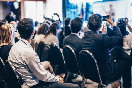 Speaker giving a talk in conference hall at business event. Rear view of unrecognizable people in audience at the conference hall. Business and entrepreneurship conceptの写真素材