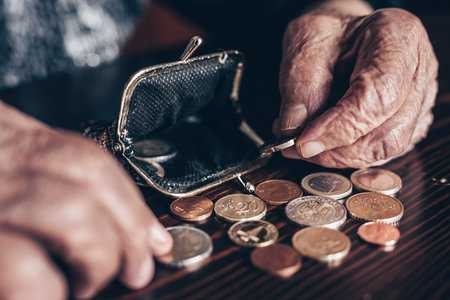 Detailed closeup photo of elderly 96 years old womans hands counting remaining coins from pension in her wallet after paying bills. Unsustainability of social transfers and pension systemの写真素材