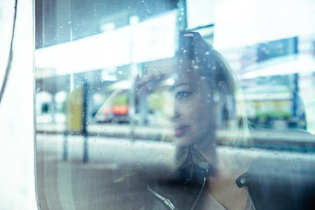 Woman traveler contemplating outdoor view from window of train. Young lady on commute travel to work...