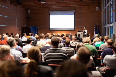 Speaker giving a talk in conference hall at business meeting event. Rear view of unrecognizable people in audience at the conference hall. Business and entrepreneurship concept.の写真素材