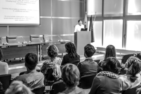 Female speaker giving presentation in lecture hall at university workshop. Audience in conference...