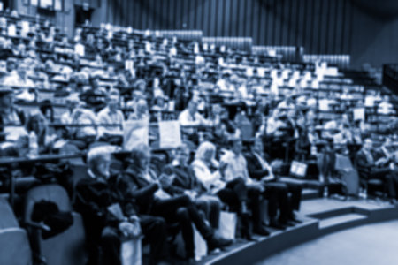 Blurred, unrecognizable, business people in the audience listening to lecture in conference hall. Business and Entrepreneurship concept. Blue toned monochrome image.の写真素材