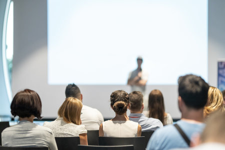Male speaker giving a talk in conference hall at business event. Audience at the conference hall. Business and Entrepreneurship concept. Focus on unrecognizable people in audience.の写真素材