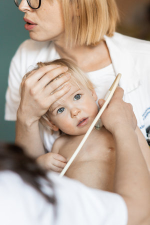 Small child being checked for heart murmur by heart ultrasound exam by cardiologist as part of regular medical checkout at pediatricianの写真素材
