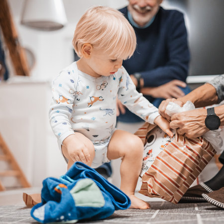 Cute little blond Caucasian toddler unpacking Christmas or Birthday present. Adorable small infant baby boy opening gift.の写真素材
