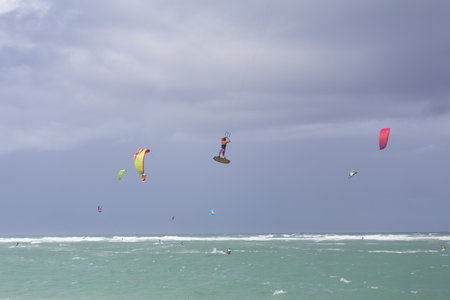 Kiteboarding. Fun in the ocean. Extreme Sport Kitesurfing. Kitesurfer jumping high in the air performing triks during kitesurfing sessionの写真素材