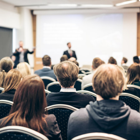 Speaker giving a talk in conference hall at business event. Rear view of unrecognizable people in audience at the conference hall. Business and entrepreneurship conceptの写真素材