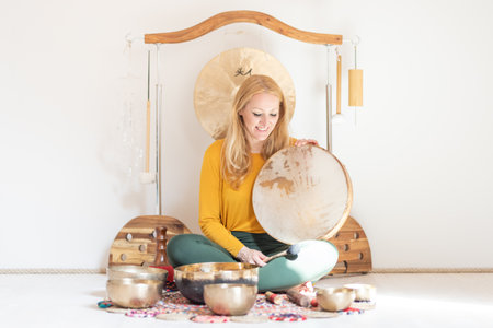 Young cheerful woman performing music therapy session with traditional instruments. Sound meditation, body healing. Seven chakras. Healthcare recreation processの写真素材