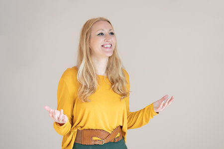 Portrait of confident beautiful woman with long blonde hair, wearing casual clothes, standing in welcoming pose with open hands.の写真素材