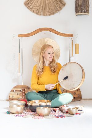 Young cheerful woman performing music therapy session with traditional instruments. Sound meditation, body healing. Seven chakras. Healthcare recreation processの写真素材
