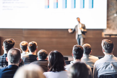 Speaker giving a talk in conference hall at business event. Rear view of unrecognizable people in audience at the conference hall. Business and entrepreneurship conceptの写真素材