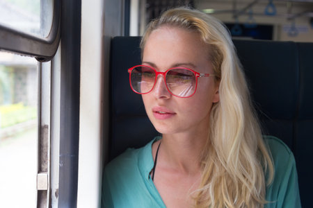 Happy smiling woman looks out from window traveling by train on most picturesque train road in Sri Lankaの写真素材