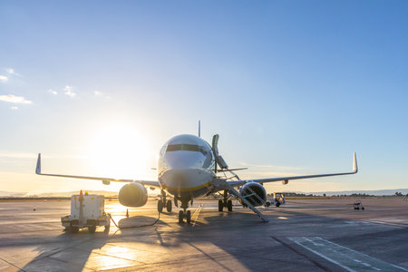 Commercial passengers airplane on airport runway in sunset.