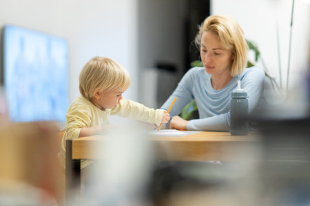 Caring young Caucasian mother and small son drawing painting in notebook at home together. Loving mom or nanny having fun learning and playing with her little 1,5 year old infant baby boy childの写真素材