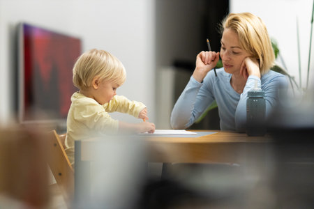 Caring young Caucasian mother and small son drawing painting in notebook at home together. Loving mom or nanny having fun learning and playing with her little 1,5 year old infant baby boy childの写真素材