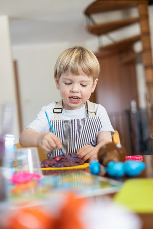 Blond boy sculpts from plasticine at home at the table. The idea and concept of the school, home...