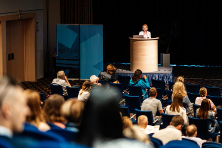 Female speaker giving a talk on corporate business conference. Unrecognizable people in audience at conference hall. Business and Entrepreneurship eventの写真素材