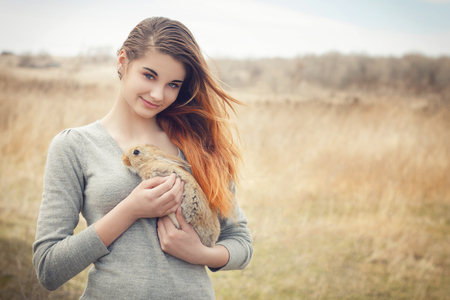 the girl with the rabbit.happy little girl holding cute fluffy Bunny.Friendship with Easter Bunny. Spring photo with beautiful young girl with her Bunny. Girl is holding a cute little rabbitの写真素材