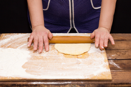 hands rolling dough with a rolling pin, on a black backgroundの写真素材