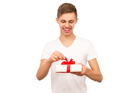 portrait of a guy with a gift, isolate, the guy in a white T-shirt gives a giftの写真素材