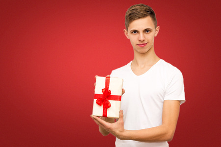 guy with a gift on a red background, portrait of a guy on a red background with a place under the inscriptionの写真素材