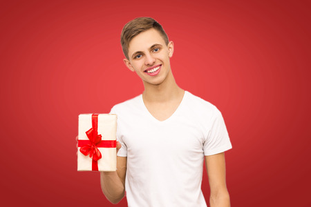 guy with a gift on a red background, portrait of a guy on a red background with a place under the inscriptionの写真素材