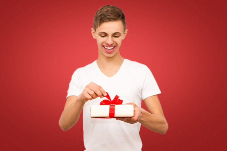guy with a gift on a red background, portrait of a guy on a red background with a place under the inscriptionの写真素材