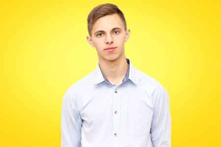 portrait of a guy on a yellow studio background, calm man in a blue shirtの写真素材