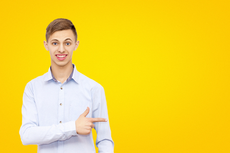 a guy pointing a finger at an advertisement, isolated on a yellow background, a man advertises a product, a place under the inscriptionの写真素材
