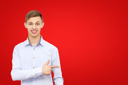 a guy pointing a finger at an advertisement, isolated on a red background, a man advertises a product, a place under the inscriptionの写真素材