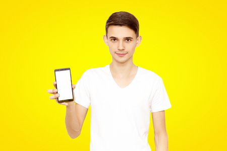 the guy in the white T-shirt advertises the phone, on a yellow background. man with phoneの写真素材
