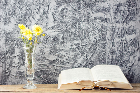 bouquet of yellow flowers with a book on a beautiful wooden background with a copy of spaceの写真素材