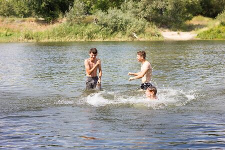 Jumping in the water. Kids have fun and splash in the water. Summer holiday concept , three friends are having fun on the riverの写真素材