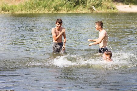 Jumping in the water. Kids have fun and splash in the water. Summer holiday concept , three friends are having fun on the riverの写真素材