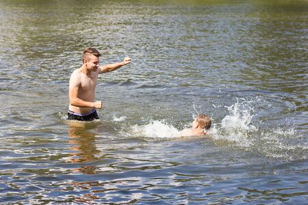 two friends are swimming in the river. Friends have fun on vacation. swimming seasonの写真素材