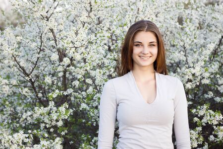 girl smiling on the background of a flowering tree. Cute girl smiling at the camera. Place under the...