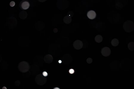 Freeze motion of white powder coming down, isolated on black, dark background. Abstract design of falling dust cloud. Particles cloud screen saver, wallpaper with copy space. Rain, snow fall conceptの写真素材