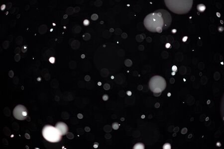 Freeze motion of white powder coming down, isolated on black, dark background. Abstract design of falling dust cloud. Particles cloud screen saver, wallpaper with copy space. Rain, snow fall conceptの写真素材