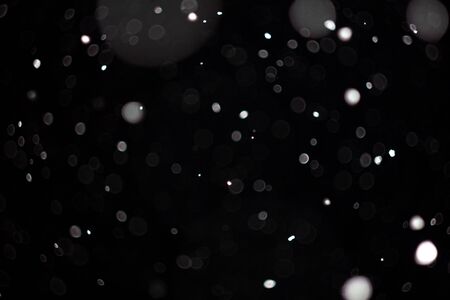 Freeze motion of white powder coming down, isolated on black, dark background. Abstract design of falling dust cloud. Particles cloud screen saver, wallpaper with copy space. Rain, snow fall conceptの写真素材