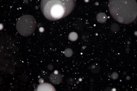 Freeze motion of white powder coming down, isolated on black, dark background. Abstract design of falling dust cloud. Particles cloud screen saver, wallpaper with copy space. Rain, snow fall conceptの写真素材