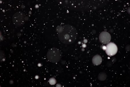 Freeze motion of white powder coming down, isolated on black, dark background. Abstract design of falling dust cloud. Particles cloud screen saver, wallpaper with copy space. Rain, snow fall conceptの写真素材